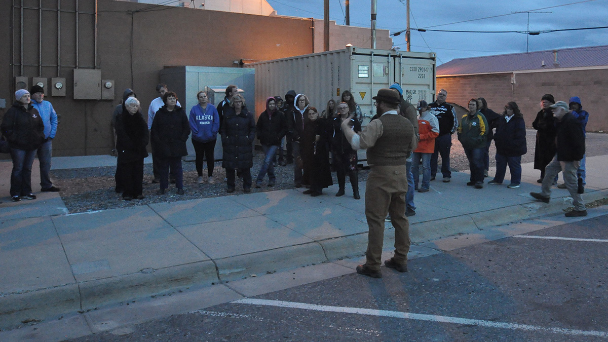 color image of Alma Law speaking to a large group of people outside of a red brick building